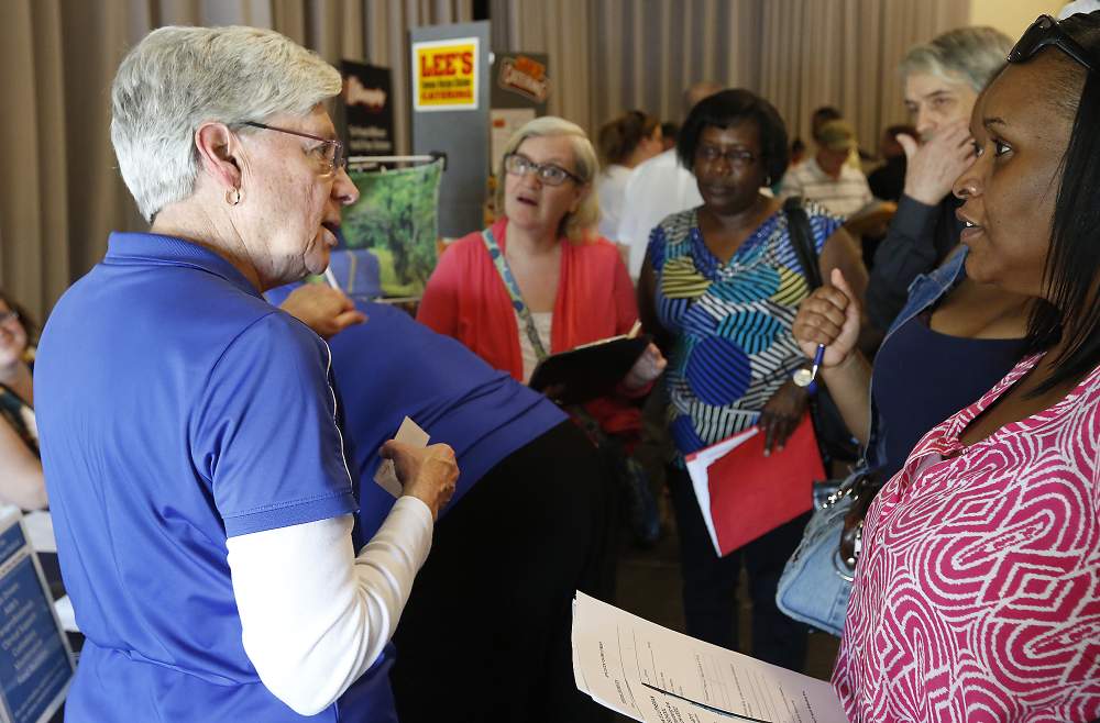 Deb Dasher,  from Springfield City Schools,  is surrounded by people as she talks about job opportunities at the Chamber of Greater Springfield and OhioMeansJobs Clark County job fair Tuesday. Bill Lackey\/Staff
